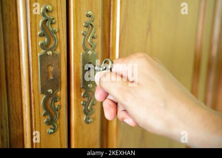 Männliche Hand legt den Schlüssel in das Schlüsselloch eines Kleiderschranks Stockfoto