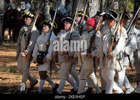 Kershaw, South Carolina, USA. 13.. November 2022. Fans des Revolutionären Krieges und leidenschaftliche Schauspieler stellen die Schlacht von Camden, SC, nach, sodass Besucher während des Krieges um die Unabhängigkeit von der britischen Herrschaft lebendige Geschichte erleben können. Die Schlacht von Camden, die 1780 ausgetragen wurde, war eine von mehreren verheerenden Niederlagen, die die Amerikaner in den frühen Phasen der britischen Militäroffensive im Süden erlitten haben. Im Bild: Koloniale Infanterie-Re-enactors marschieren in den Kampf (Bild: © Robin Rayne/ZUMA Press Wire) Stockfoto