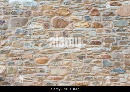 Wand eines gestapelten flachen Steinhauses. Hintergrund und Textur für Text oder Bild. Stockfoto