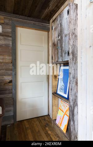 Alte, wiederaufbereitete Scheune Holz Wandeinheit und zeitgenössische weiß lackierte geschlossene Badezimmertür im rustikalen 11,5 x 32 Fuß offenen Design Minihaus. Stockfoto