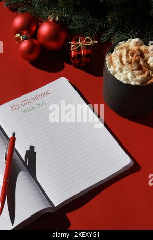 Rote Weihnachtskomposition mit heißer Schokolade und Notizbuch für Wunschliste Stockfoto