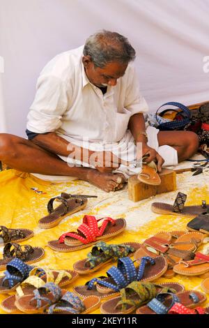 Pune, Indien - Nov 11 2022: Ein traditioneller Schuhmacher, der auf dem lokalen Markt traditionelle bunte Schuhe und Hausschuhe herstellt. Stockfoto