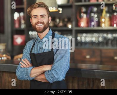 Kaffee ist meine Stärke. Porträt eines jungen Barista, der in einem Café arbeitet. Stockfoto