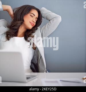 Kein Stress in diesem Büro. Eine junge Geschäftsfrau, die entspannt auf ihrem Laptop arbeitet. Stockfoto