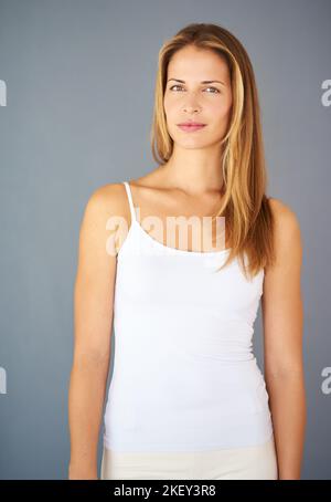 Ich glaube, ich kann und werde. Studioaufnahme einer attraktiven jungen Frau, die vor grauem Hintergrund posiert. Stockfoto