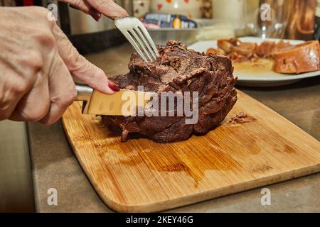 Der Koch schneidet Scheiben aus einem Stück lang gegartem Rindfleisch Stockfoto