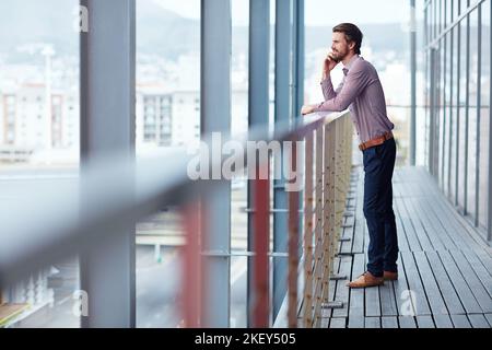Ein junger Geschäftsmann, der vor einem Bürogebäude telefoniert. Stockfoto