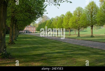 Malerische Aussicht auf einen von Bäumen gesäumten Pfad, der zu einem wunderschönen viktorianischen englischen Landhaus führt Stockfoto