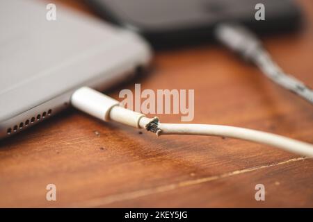 Nahaufnahme gebrochenes weißes Ladekabel für Smartphone. Stockfoto