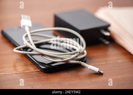 Nahaufnahme gebrochenes weißes Ladekabel für Smartphone. Stockfoto