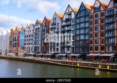 Danzig, Polen Mai 2022, moderne Gebäude über dem Motlawa-Fluss in der Altstadt. Tourismus auf dem Motlawa River. Neue Apartments-Architektur auf Granary Island Glasfenster mit Reflexionen. Touristisches Reiseziel Stockfoto