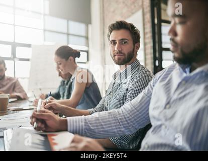 Das ist das Team, das es zu schlagen gilt. Porträt eines Geschäftsmannes, der in einer Sitzung sitzt. Stockfoto