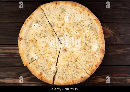 Heiße Pizza, vier Käsesorten mit dünner Kruste auf dunklem Holzhintergrund. Stockfoto