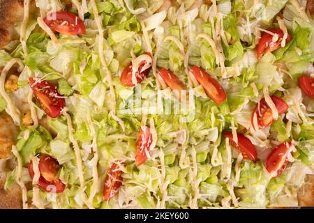 Pizza Hintergrund - Makroaufnahme von Pizza Caesar Kirschtomaten, Eisbergsalat, Huhn und Parmesan-Käse. Stockfoto