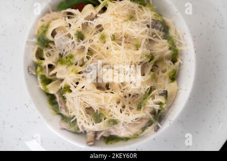 Italienische cremige Pasta mit Huhn und Pilzen mit Basilikumsoße, Draufsicht. Traditionelles italienisches Mittagessen Stockfoto