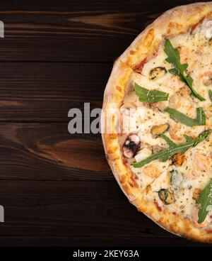 Italienische Pizza mit Meeresfrüchten, Garnelen, Mozzarella und Muscheln auf einem Holztisch. Stockfoto