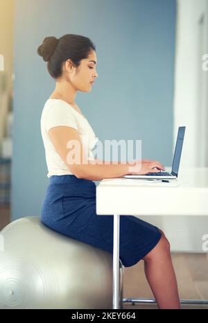 Eine junge Geschäftsfrau, die zu Hause an ihrem Laptop arbeitet. Stockfoto