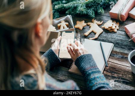 Eine Frau macht Pläne für das neue Jahr 2023 und hält ein Telefon mit einem Kalender auf dem Bildschirm. Stockfoto