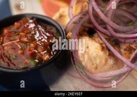 Kebabs Hintergrund - gegrilltes Fleisch mit Ketchup, Kebab mit Gemüse auf blauem Teller. Speisekarte des BBQ-Restaurants. Makroaufnahme Stockfoto