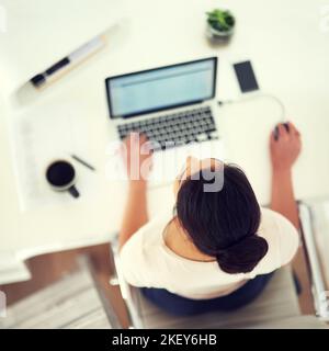 Business aus der Vogelperspektive. High-Angle-Aufnahme einer jungen Geschäftsfrau, die zu Hause an ihrem Laptop arbeitet. Stockfoto
