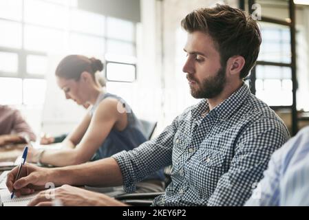 Notieren Sie sich alle wichtigen Punkte. Ein Team von Geschäftsleuten, die sich in einem Büro treffen. Stockfoto