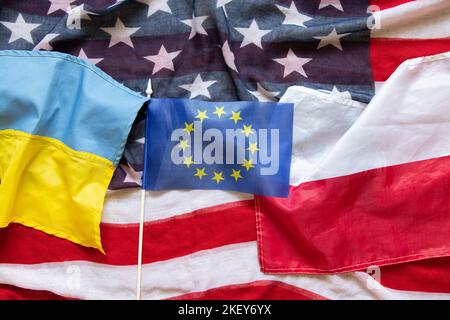 Flaggen von Amerika, der Ukraine, Polen, der Europäischen Union liegen als Hintergrund auf dem Tisch, Freundschaft der Völker während des Krieges Stockfoto