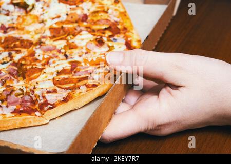 Lieferung von Lebensmitteln. Hand hält einen offenen Karton mit Pizza-Nahaufnahme Stockfoto