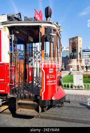 Istanbul, Türkei - September 2 2022: Nostalgische Taksim Tunel Red Tram, oder Tramvay, mit Republic Monument oder Cumhuriyet Aniti Statue im Hintergrund, am Taksim Square, Beyoglu Bezirk, Stadtzentrum Stockfoto