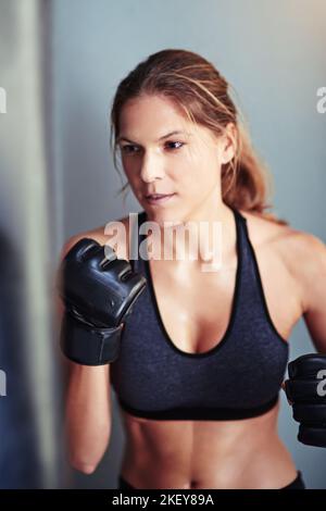 Shes bekam die Kraft. Eine Boxerin trainiert mit einem Boxsack. Stockfoto