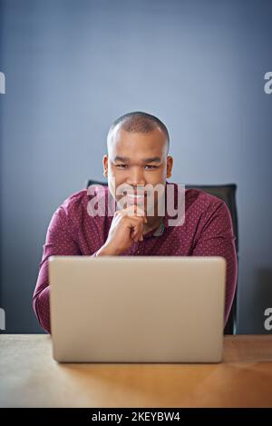 Ein engagierter Mitarbeiter. Ein Geschäftsmann, der an seinem Schreibtisch an seinem Laptop arbeitet. Stockfoto