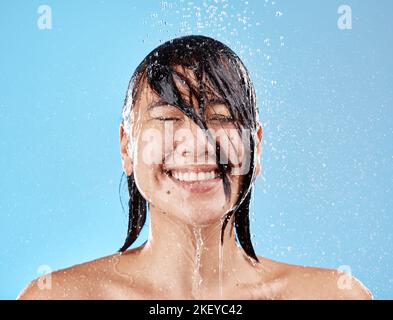 Dusche, Frau und Wasser mit Gesichtsreinigung für Reinigung, Reinigung und Hygiene auf blauem Studiohintergrund. Bad, Dusche und asiatische weibliche Reinigung Stockfoto