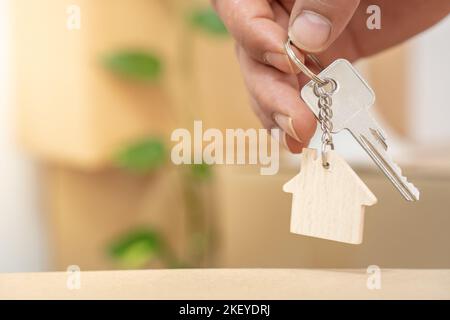 Hand hält neue Home-Schlüssel auf Haus geformten Schlüsselanhänger realen Zustand Umzug Umzug Konzept Stockfoto