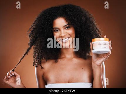 Haarpflege, Werbung und Porträt einer schwarzen Frau mit Afro und Produkt vor braunem Studiohintergrund. Marketing, Lächeln und Gesicht eines Stockfoto