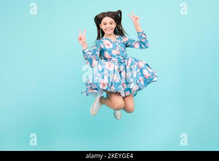 In voller Größe Foto von positiven Teenager-Mädchen springen mit Bewegung Sommerkleid, Mode Kinder Outfit isoliert auf blauem Hintergrund. Aufgeregt Teenager, erstaunt und Stockfoto