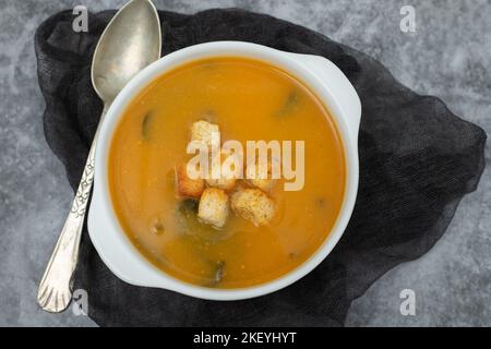 Gemüsesuppe mit trockenem Brot in weißer Schüssel auf Keramik Stockfoto