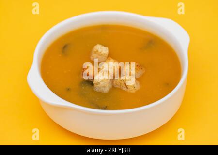 Gemüsesuppe mit trockenem Brot in weißer Schüssel auf gelb Stockfoto
