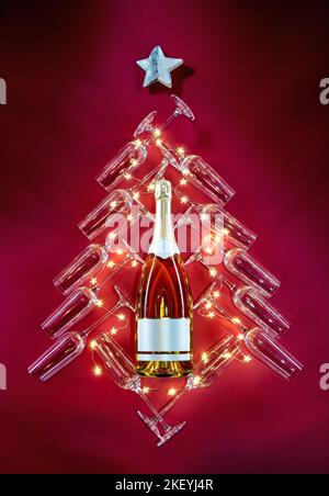 Silhouette eines festlichen Baumes, eine Flasche Champagner, umgeben von Gläsern und Sternen auf rotem Hintergrund. Frohe Weihnachten und ein glückliches neues Jahr Konzept Stockfoto