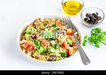 Gesunder Quinoa-Salat in einer Schüssel mit Olivenöl, Olive, Petersilie auf weißem Hintergrund Stockfoto