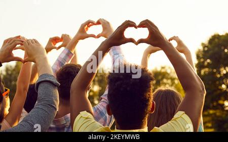 Gruppe glücklicher multirassischer Menschen, die auf Frieden hoffen und herzförmige Gesten tun Stockfoto
