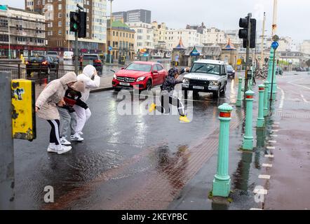 Brighton UK 15. November 2022 - Fußgänger versuchen, dem Regen und den Pfützen an der Küste von Brighton bei starkem Regen und starken Winden auszuweichen, während Stürme heute Morgen über die Südküste ziehen : Credit Simon Dack / Alamy Live News Stockfoto