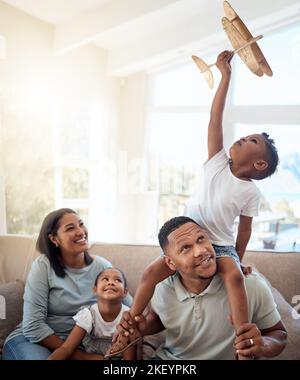 Glückliche Familie spielt Wohnzimmer mit Spielzeug Flugzeug für lustige Spiele, Freiheit und Energie zusammen in Familie zu Hause. Eltern, Kinder und fliegende Flugzeugspielzeuge Stockfoto