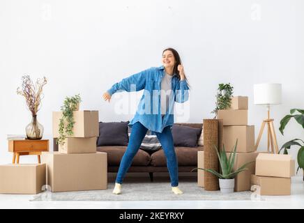 Junge glückliche Frau tanzt glücklich, nachdem sie in ihr neues Haus oder ihre neue Wohnung umzog Stockfoto