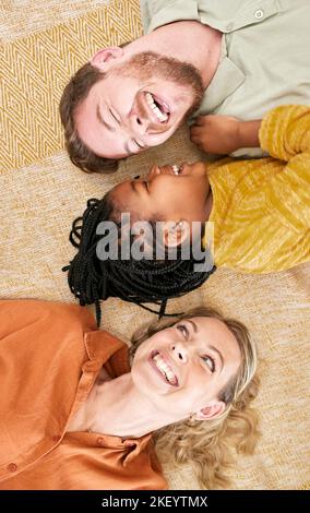 Adoption und Familie mit Mädchen von oben auf dem Boden liegend, pflegen Familie zusammen. Mama, Papa und Kind liegen auf dem Teppich und spielen, lieben und amüsieren sich Stockfoto