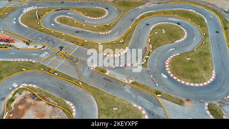 Luftaufnahme der Go-Kart-Bahn von oben von der Drohne. Kart-Rennfahrer fahren auf der offenen Piste. Stockfoto