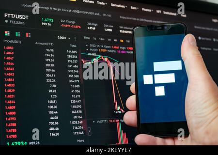 Mann mit Telefon und FTX-Logo. Globaler Rückgang der Kryptowährungskurve – FTT-Token fiel auf dem Bildschirm der App auf den Kryptowährungsbörsen des Diagramms. FTX-Austausch b Stockfoto