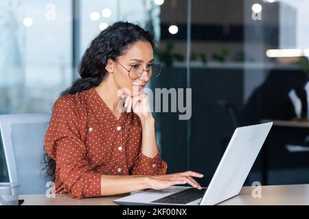 Erfolgreiche indische Frau Entwickler Programmierer arbeiten im modernen Büro, mit Laptop bei der Arbeit, um Programm-Software-Code zu schreiben, lächelnd und glücklich Startup. Stockfoto