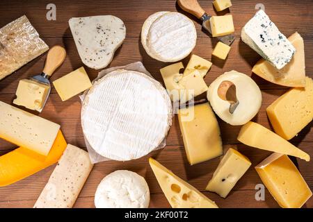 Verschiedene Käsesorten. Käseplatte mit verschiedenen Käse, mit Trauben, Nüssen, Käsemesser und Gewürzen, Holzhintergrund Kopierraum Stockfoto