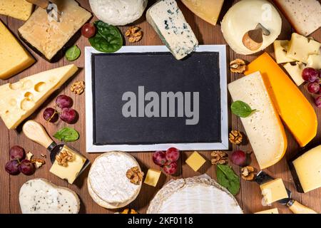 Verschiedene Käsesorten. Käseplatte mit verschiedenen Käse, mit Trauben, Nüssen, Käsemesser und Gewürzen, Holzhintergrund Kopierraum Stockfoto