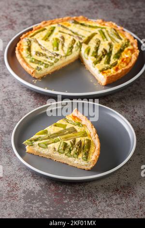 Spargel Cheese Pie eine leichte und kitschige Torte, die aus Eiern, Spargel und Zwiebeln in Nahaufnahme auf einem Teller auf dem Tisch zubereitet wird. Vertikal Stockfoto