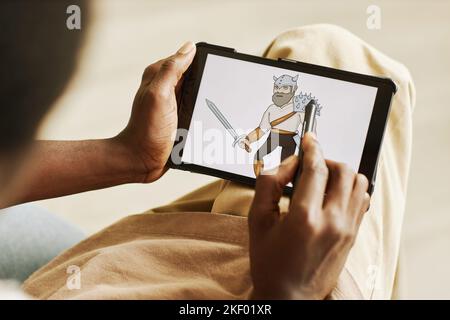 Hände von jungen schwarzen Mann mit Stift Zeichnung Grafik Bild des Kriegers auf Tablet-Bildschirm, während die Schaffung einer neuen Sammlung von digitalen Kunstwerken Stockfoto